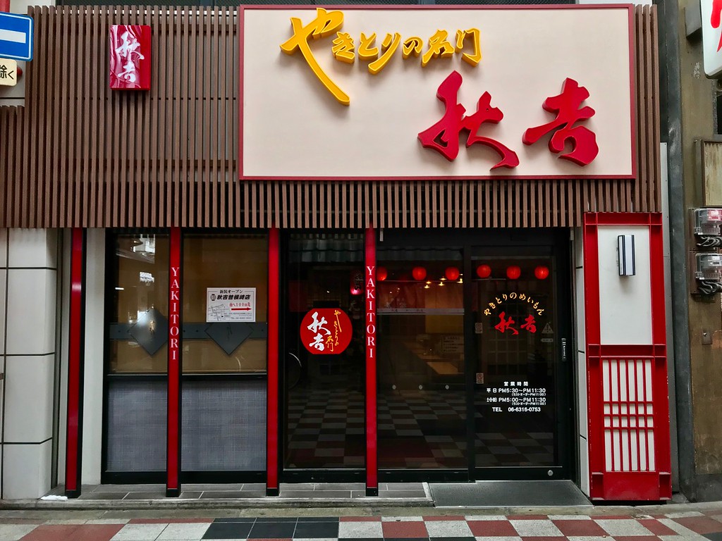 Front of Akiyoshi restaurant with a large yellow and red sign that says the store's name.