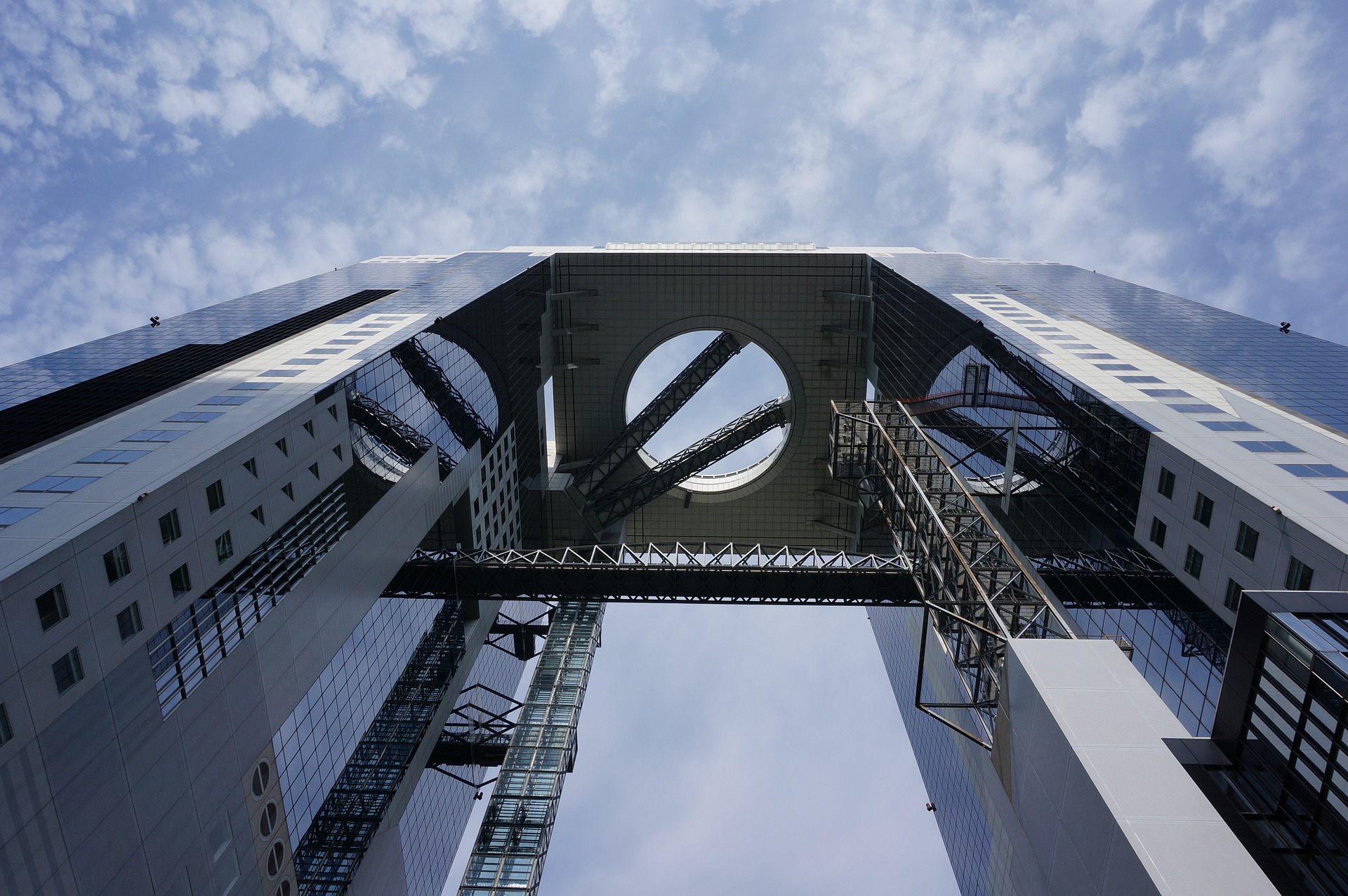 A picture of the Umeda Sky Building from the ground, showing the sky through the middle hole of the towers.